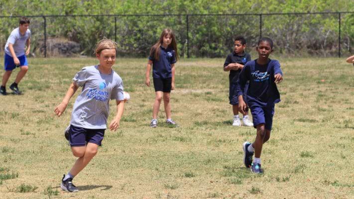 Atlantis Academy students playing in a field outside